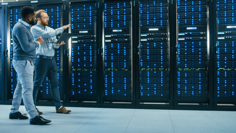 two people talking while walking past servers inside a data center