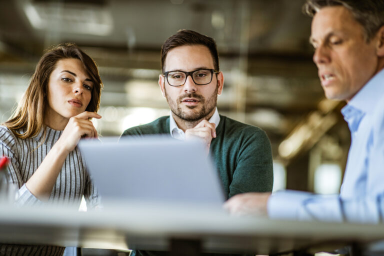 3 investors gather around a laptop