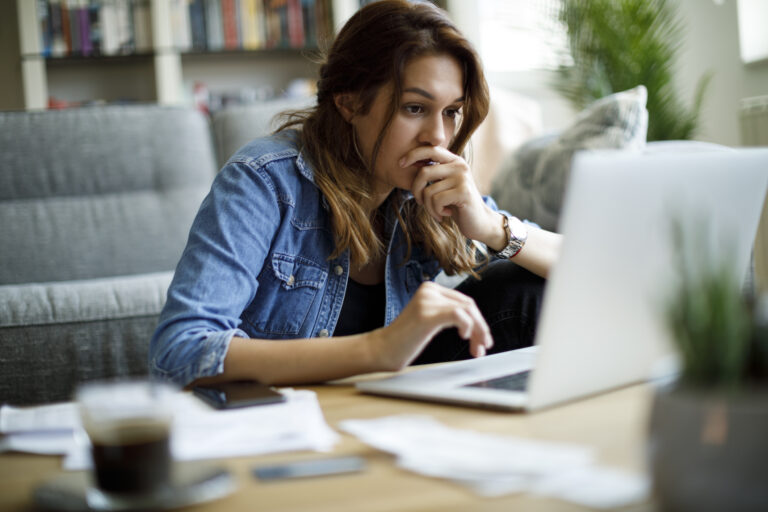 investor looks worried at computer in a living room setting