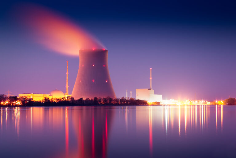 nuclear power plant next to a pond glowing red at sunset