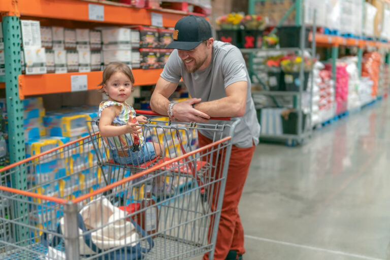 person pushing a wagon with a child in a warehouse store