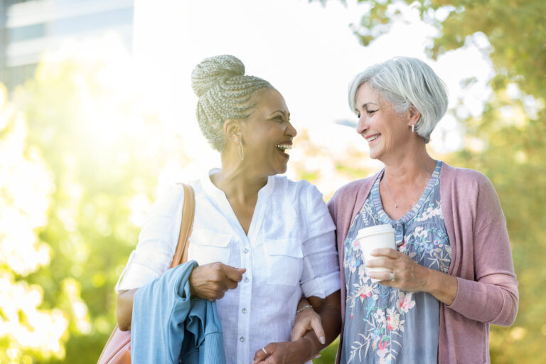 two older people walking outside smiling