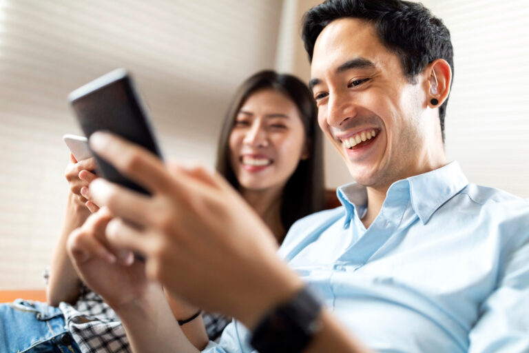 2 people looking at phones and smiling