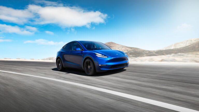 a blue tesla car driving on an open road