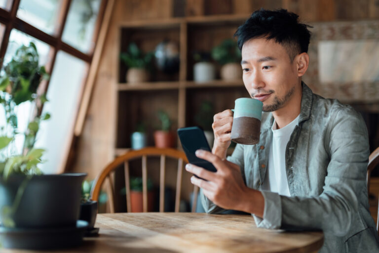 person sitting drinking coffee with a mobile phone