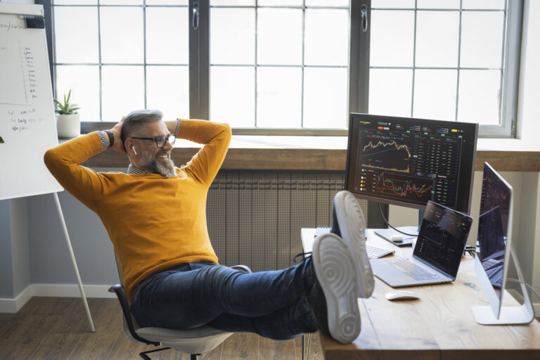 relaxed investor smiling with feet up on desk