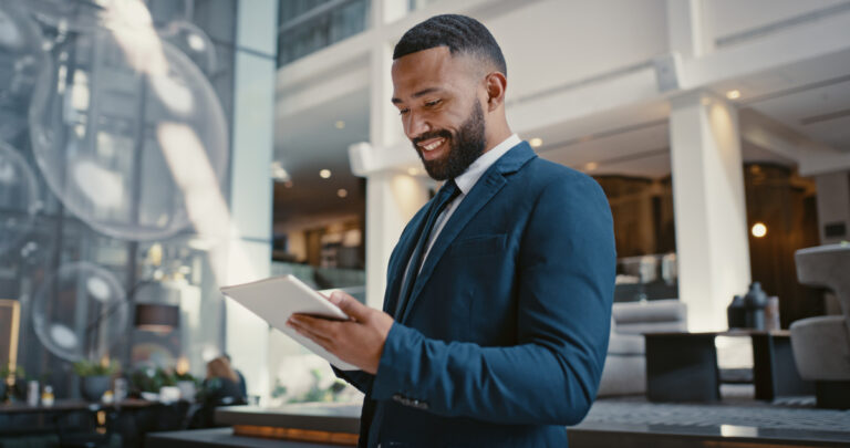 a person wearing professional attire and smiling while holding a tablet in a commercial building
